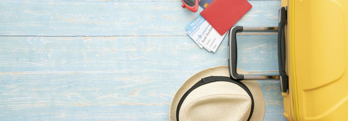 Holiday suitcase, flipflops, sunglasses, sunhat, passport and boarding passes.